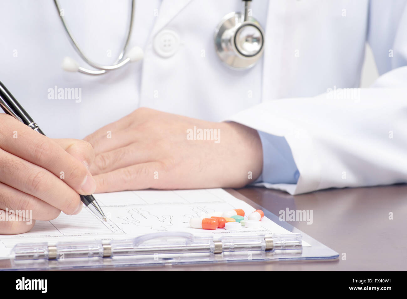 Ein männlicher Arzt schriftlich über die medizinische Form mit dem Stethoskop in der Nähe Stockfoto