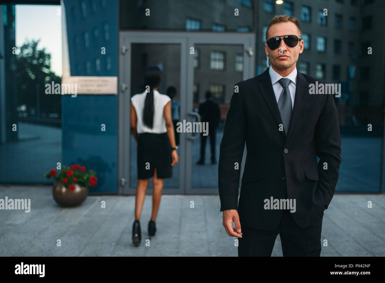 Ernsthafte Leibwächter in Anzug und Sonnenbrille, Bewachung Stockfoto