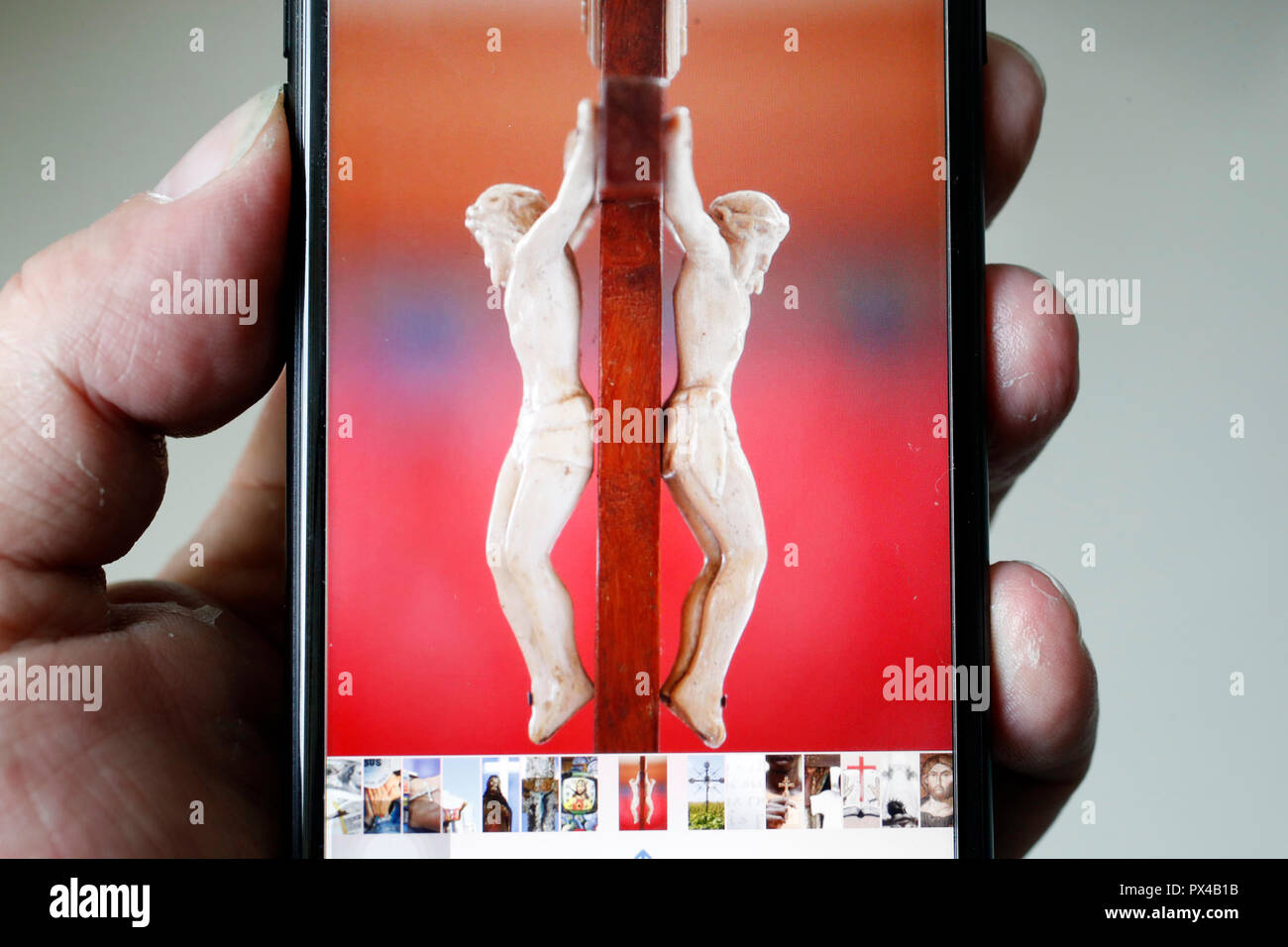 Der Mensch auf der Suche nach einem Bild von Jesus auf einem Smartphone. Stockfoto