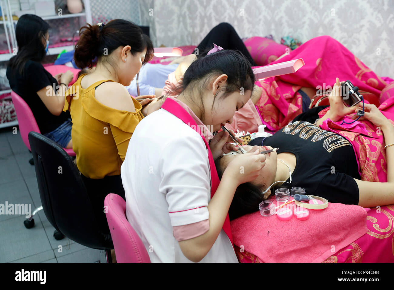 Vietnamesische Beauty Salon. Kosmetikerin Anwendung verlängert die Wimpern zu Frau. Ho Chi Minh City. Vietnam. Stockfoto