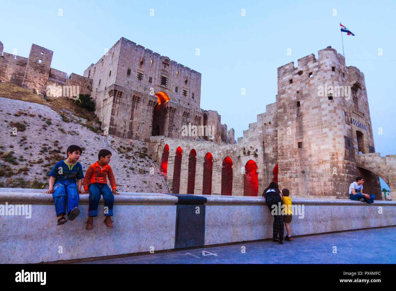 Aleppo Aleppo Governatorat, Syrien: Menschen sitzen außerhalb der Zitadelle von Aleppo in der Dämmerung beleuchtet, einen großen mittelalterlichen befestigten Palast im Zentrum von t Stockfoto