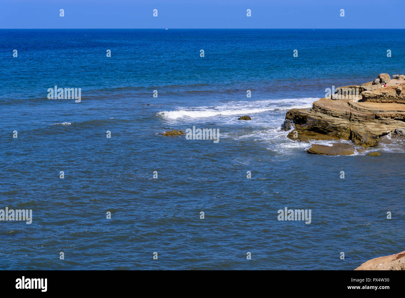 Blick auf Meer und Wellen auf die Felsen unter einem blauen Himmel. Stockfoto