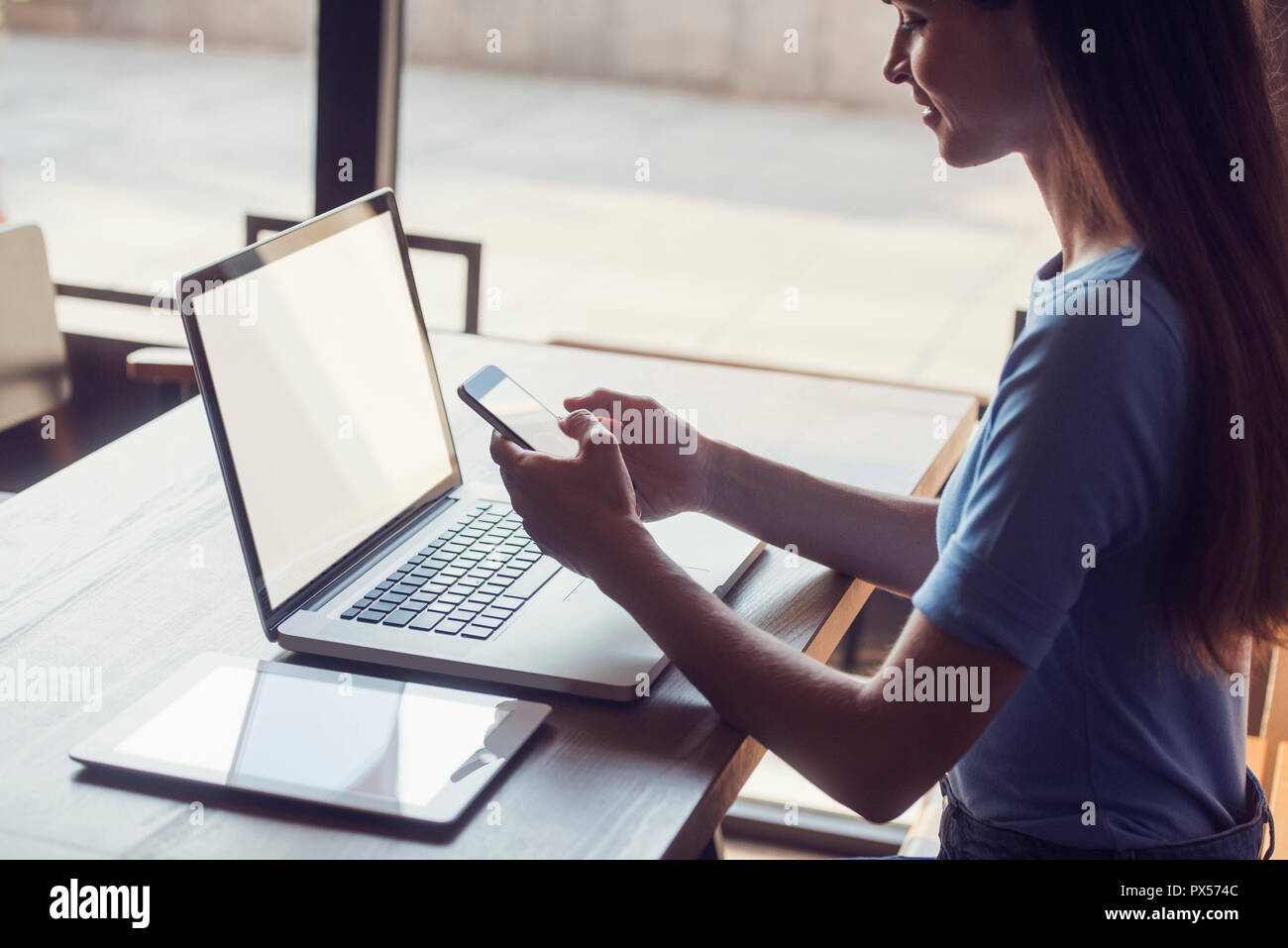 Nahaufnahme multitasking Frau mit Tablet-PC, Laptop und Handy, mit leeren Bildschirmen, in Gebäuden auf einem Tisch Stockfoto