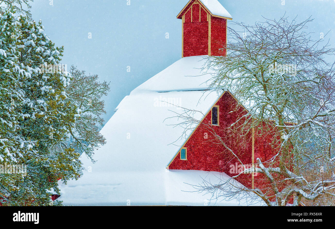 Eine gut gepflegte Rote Scheune steht in den fallenden Schnee in ländlicher Umgebung. Stockfoto