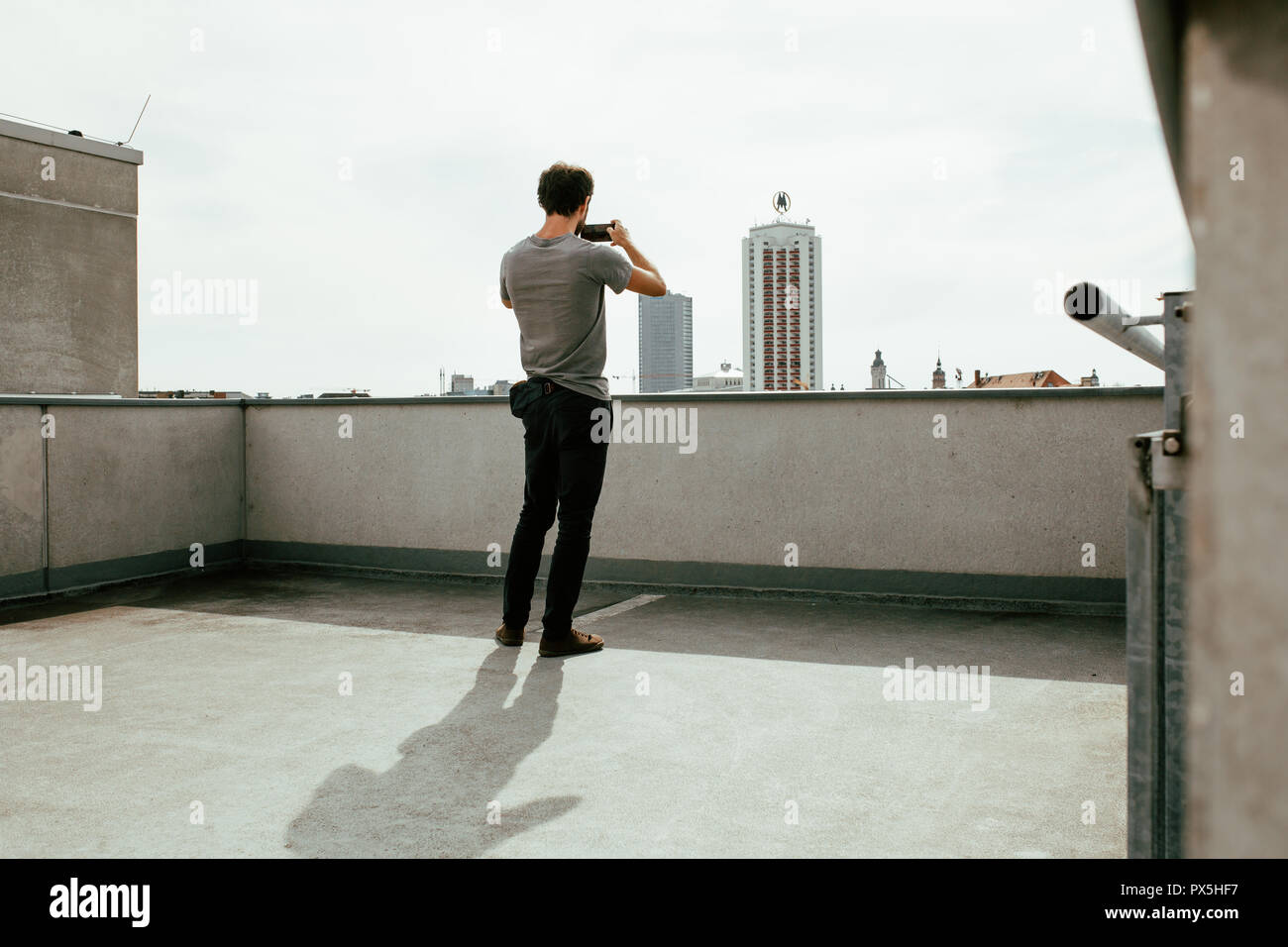 Foto der Rückseite des jungen Mann Fotografieren einer Skyline der Stadt mit seinem Smartphone Stockfoto