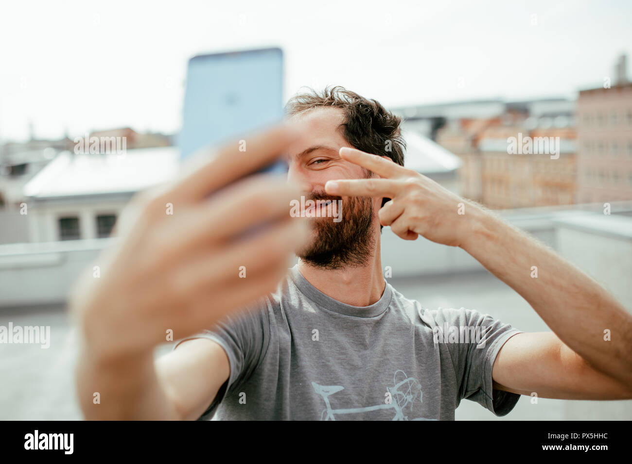 Frontalansicht des Jungen bärtigen Mann selbst fotografieren mit seinem Smartphone Stockfoto