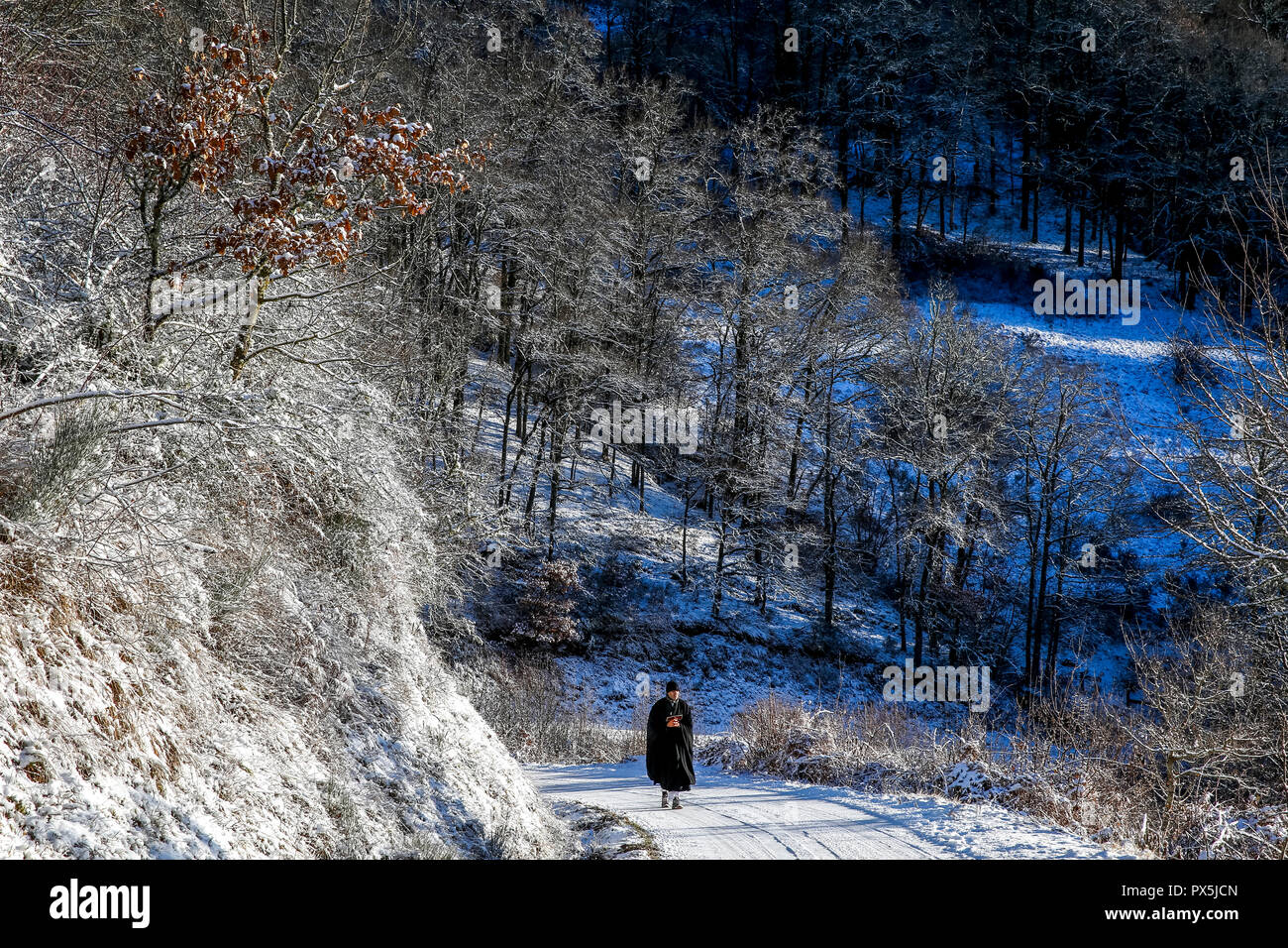 Mann zu Fuß auf einer verschneiten Straße während ein Zen sesshin (Retreats) in Lanau, Cantal. Frankreich. Stockfoto