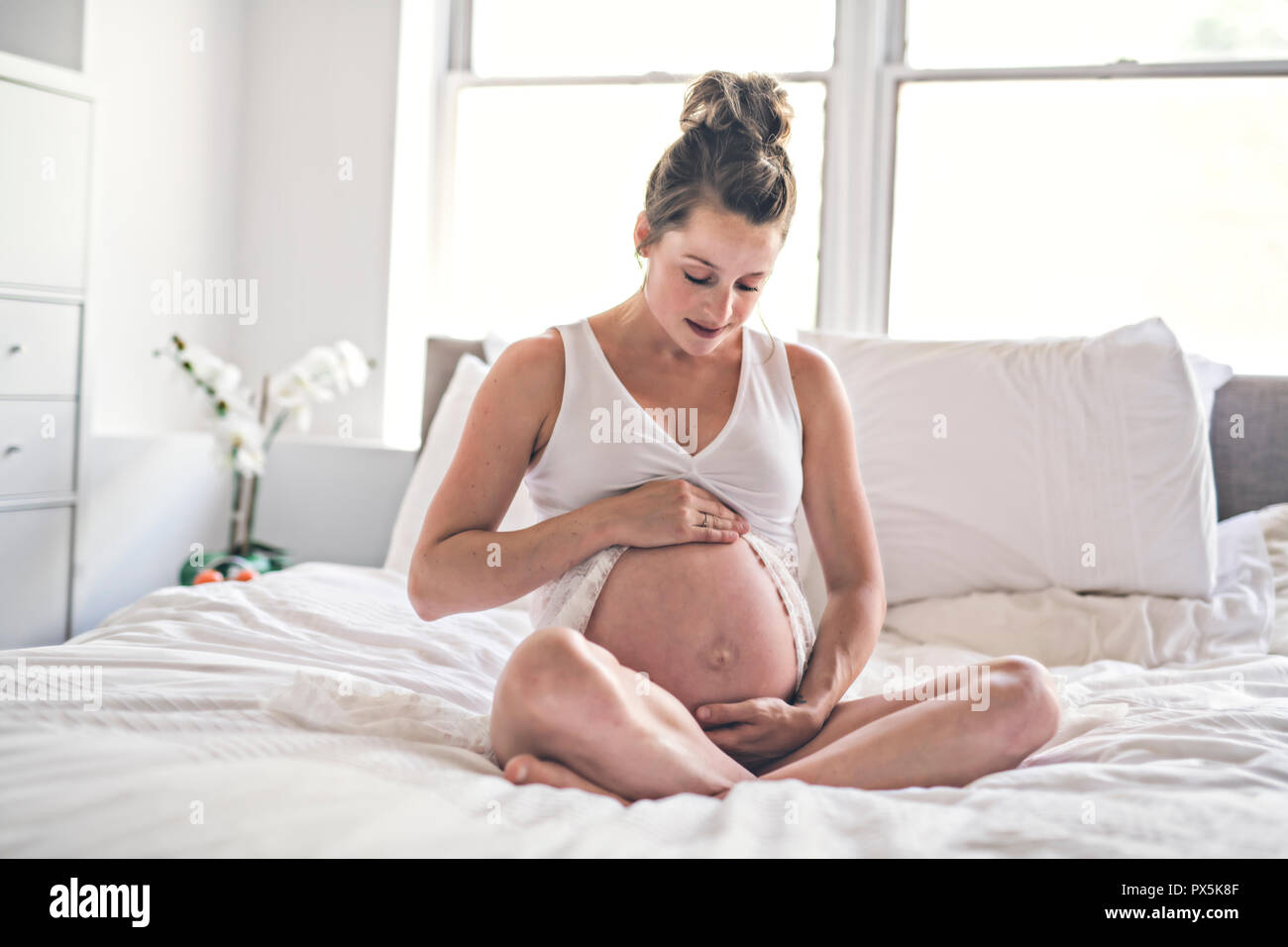 Eine glückliche Schwangerschaft auf dem Bett zu Hause sitzen Stockfoto