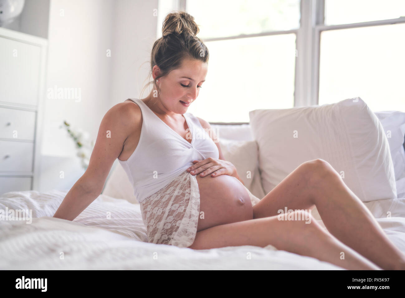 Eine glückliche Schwangerschaft auf dem Bett zu Hause sitzen Stockfoto