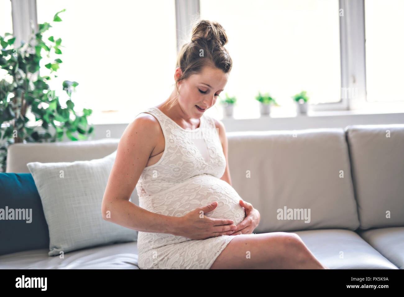 Eine glückliche Schwangerschaft auf dem Sofa zu Hause sitzen Stockfoto