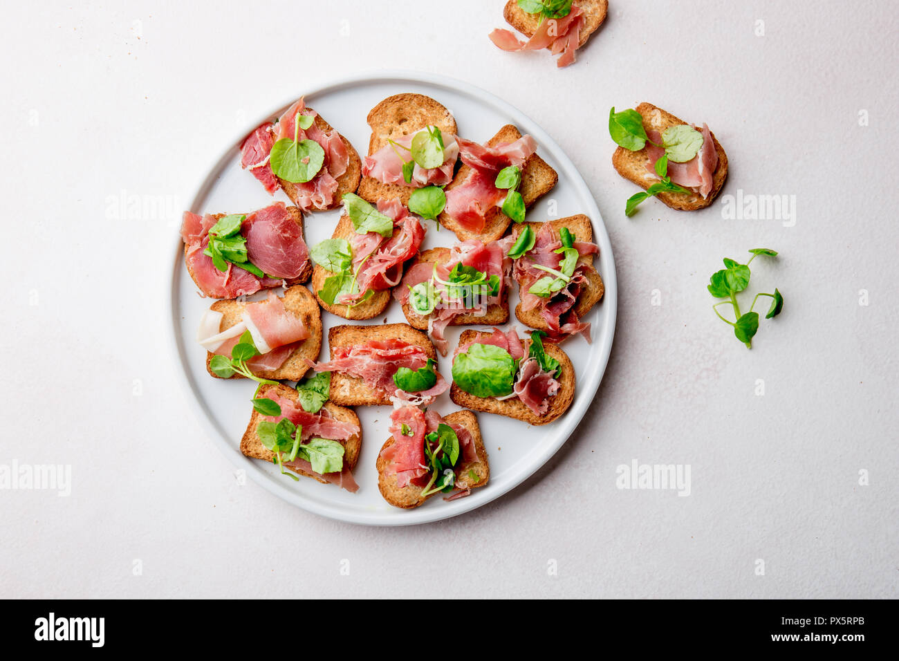 Mini offene Sandwiches mit Jamon Serrano auf weiße Platte. Stockfoto