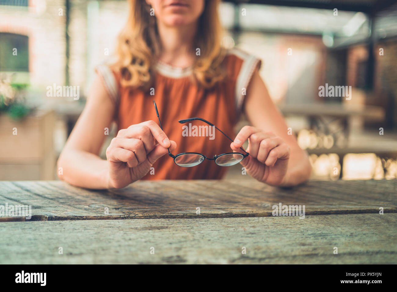 Eine junge Frau sitzt an einem Tisch mit ein paar Gläser Stockfoto