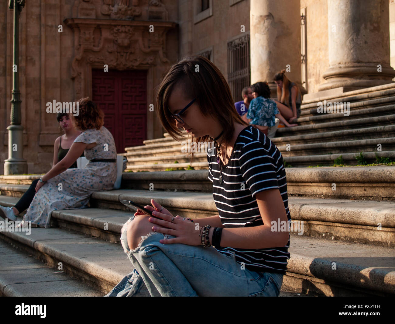 Eine junge Frau mit einer Tablette auf der Treppe von einer Universität in einem Campus der Universität Stockfoto