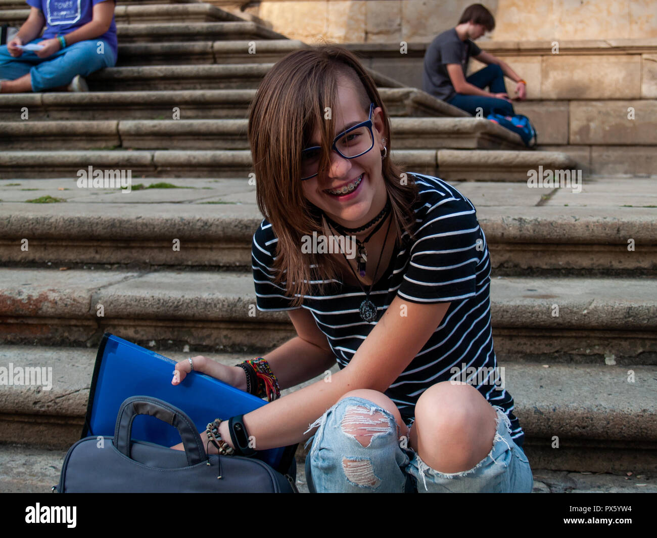 Ein Teenager Frau Studium mit einem Binder auf der Treppe einer Universität in einem Campus der Universität Stockfoto