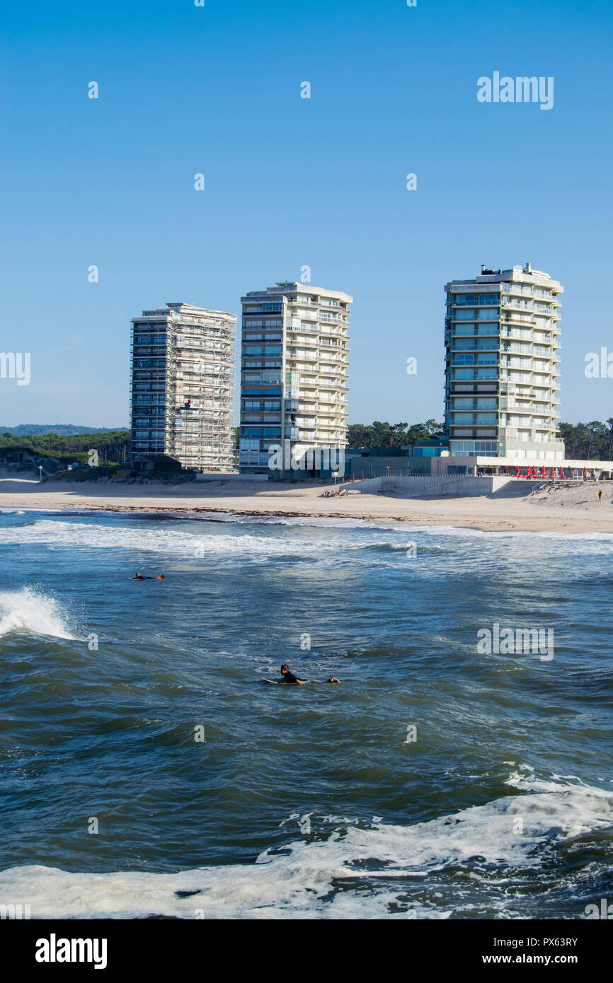 Ofir Strand in Portugal, Surfspot. Surfer auf dem Wasser mit großen Gebäuden im Hintergrund. Ozean schwellen Energie, Wassersport. Stockfoto