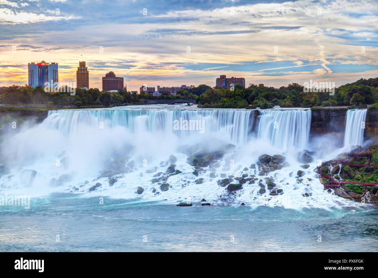 Sonnenaufgang über American Falls und Bridal Veil Falls, Niagara Falls, New York State, USA, mit Skyline im Hintergrund. Stockfoto