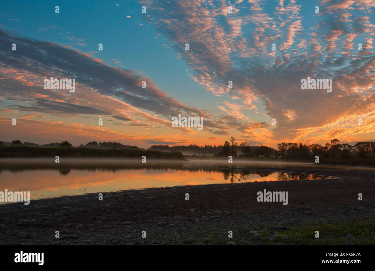 In rot, rosa und gelbe Wolken bei Sonnenaufgang hervorgehoben, ihre Reflexion im Wasser und feinen Nebel. Schöne, mystische, Oktober Morgen am See. P Stockfoto