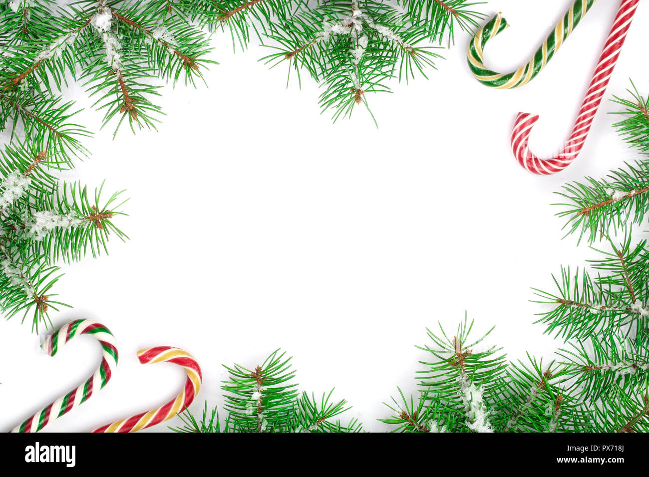 Weihnachten Rahmen der Fir Tree Branch mit Zuckerstangen und Schnee auf weißem Hintergrund mit Kopie Platz für Ihren Text isoliert. Ansicht von oben. Stockfoto