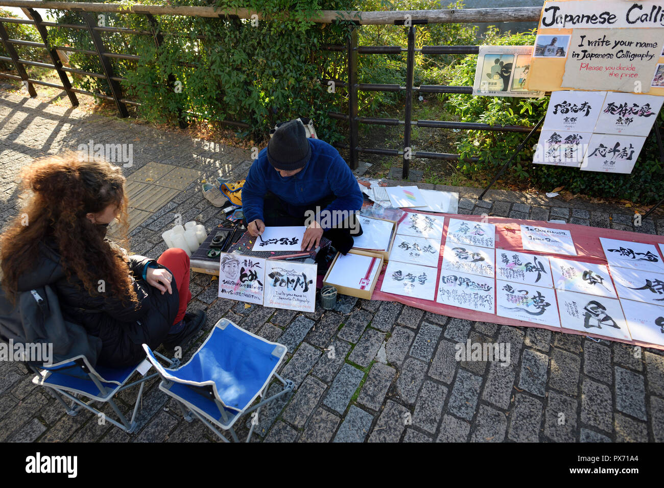 Frau touristische erhält ihren Namen in japanischen Schriftzeichen durch eine Straße artist Kalligraphen in Kyoto, Japan geschrieben Stockfoto