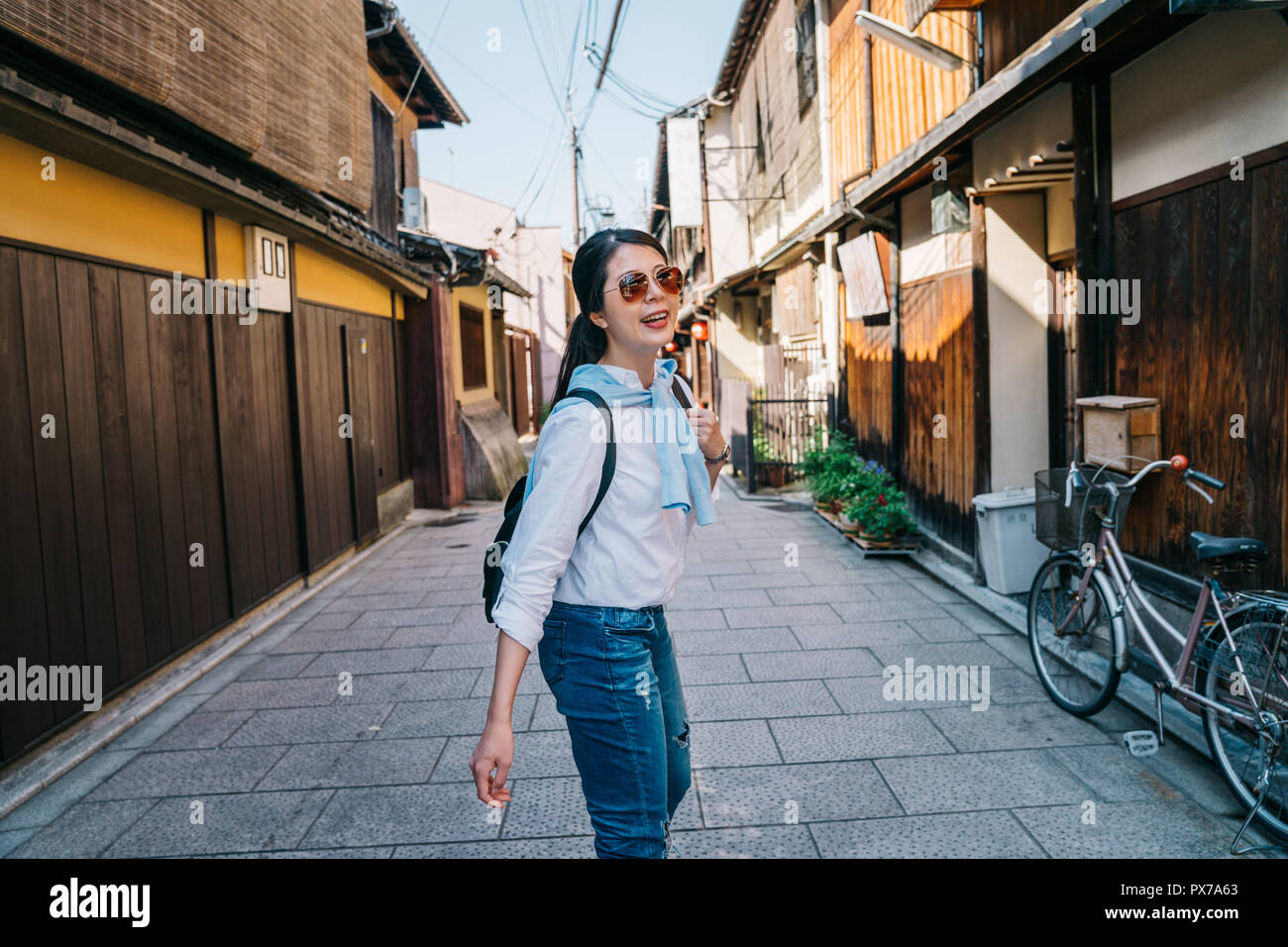 Attraktive lady freudig zu Fuß auf der Straße und zurück drehen, um sicherzustellen, dass Ihr Freund Sie folgende ist. Reisen Japan Sommerurlaub Mädchen genießen Stockfoto