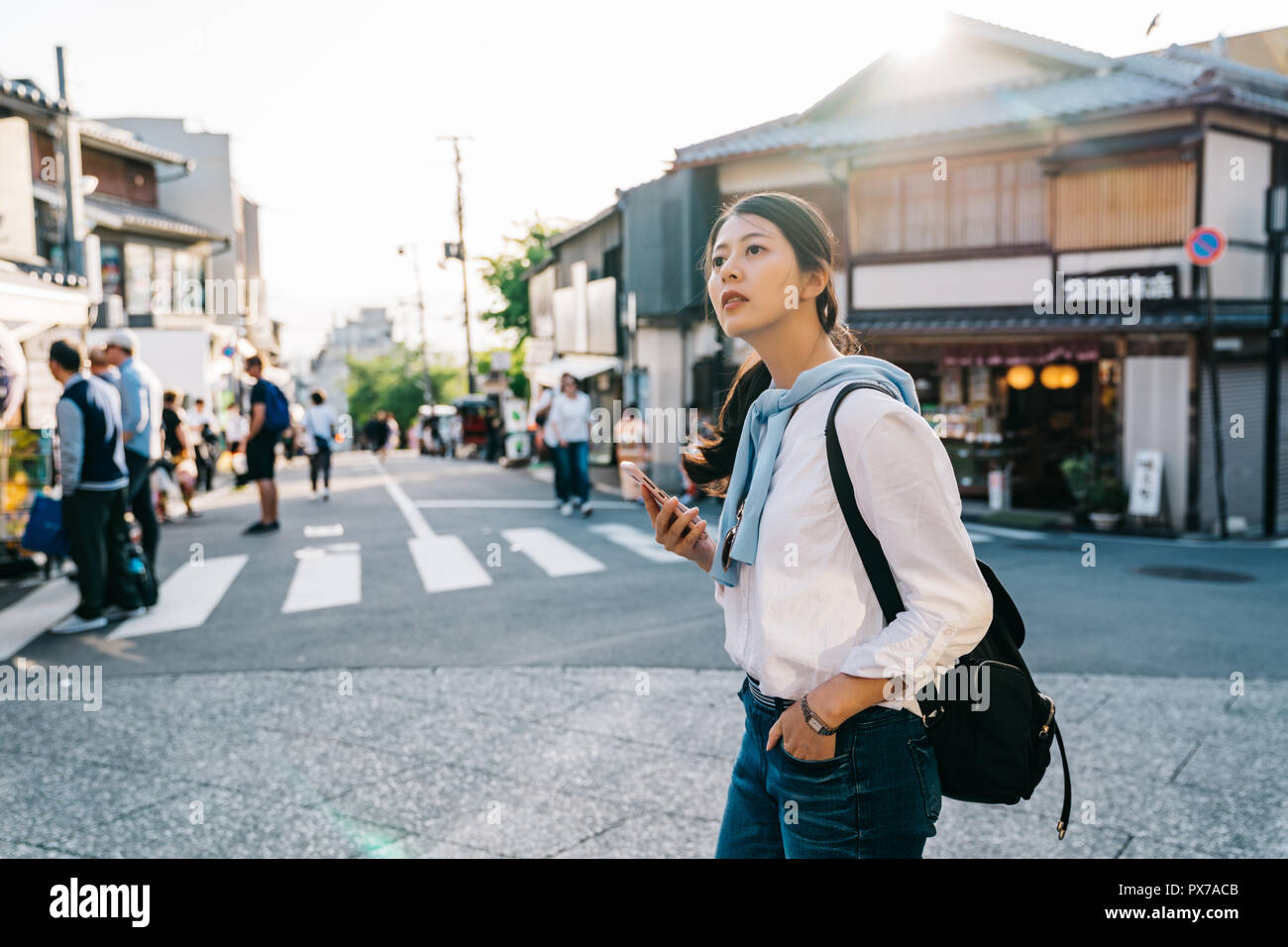 Schöne Traveler die Straße überqueren und auf die online Karte im Hotel in Kyoto. touristischen Besuch der Stadt mit online Japan Reiseführer zu gelangen Stockfoto