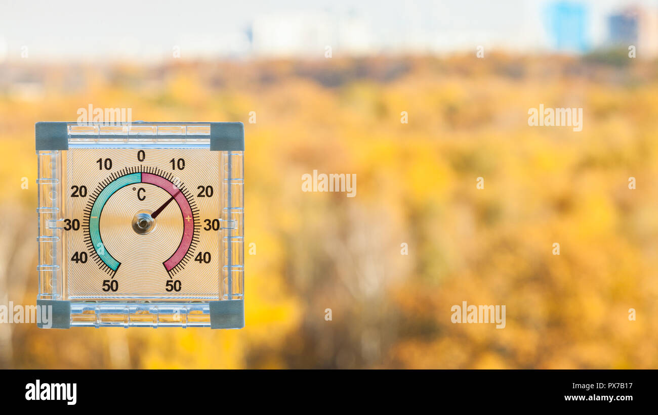 Outdoor Thermometer auf home Fenster und verschwommen gelb Urban Garden auf Hintergrund im sonnigen warmen Herbst Tag Stockfoto