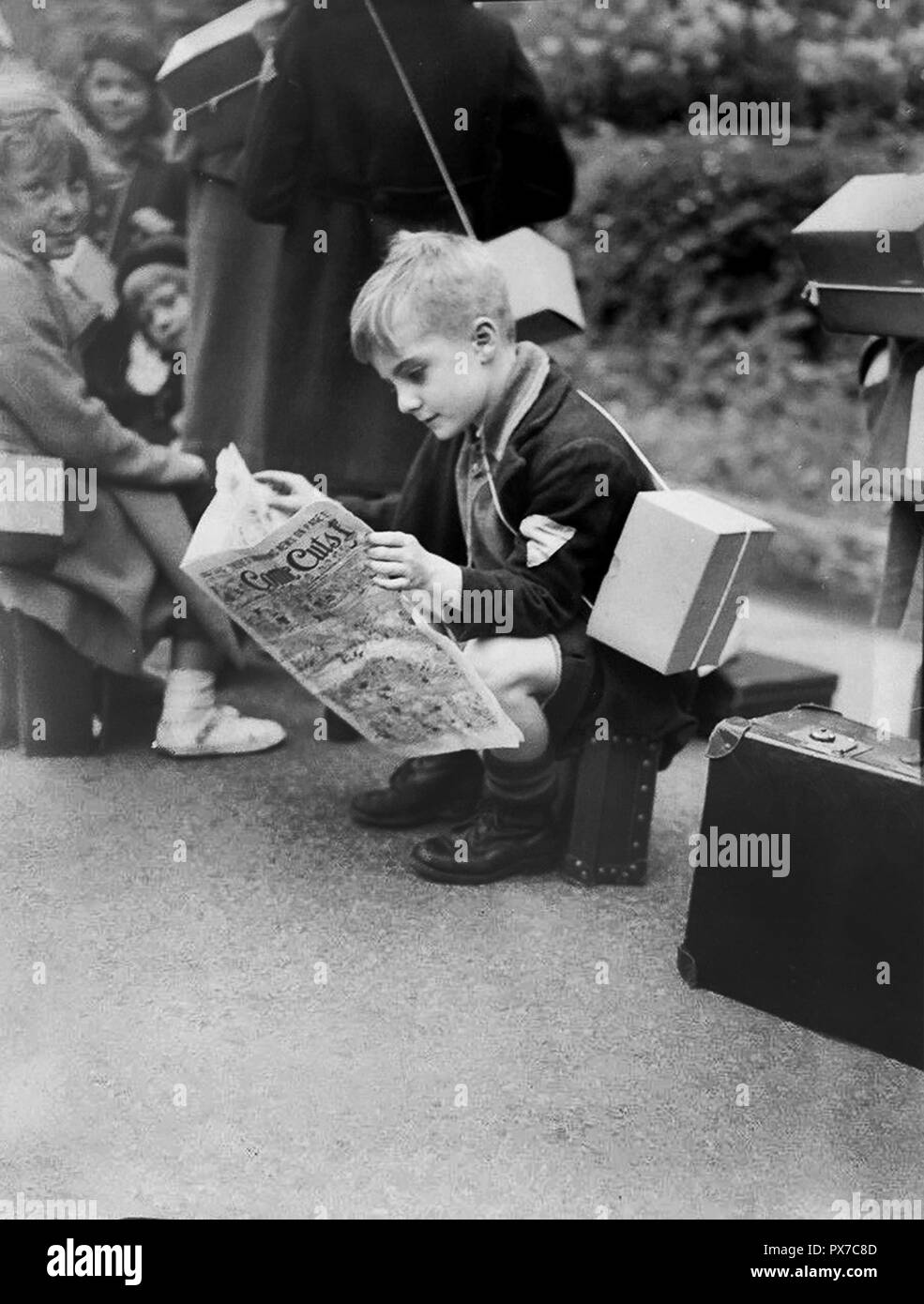 Der Junge liest die Zeitschrift Comic Cuts, während er auf den Transport für die Evakuierung während des Zweiten Weltkriegs in London 1941 wartet Stockfoto