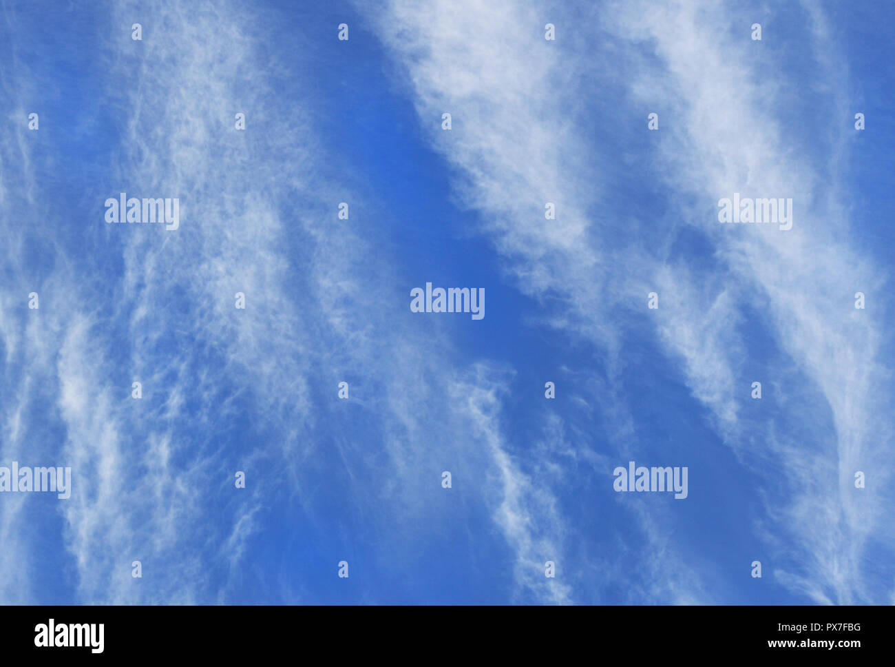 Weiß wispy Cirrus Wolken bilden in vertikaler Richtung gegen den tiefblauen Himmel Stockfoto