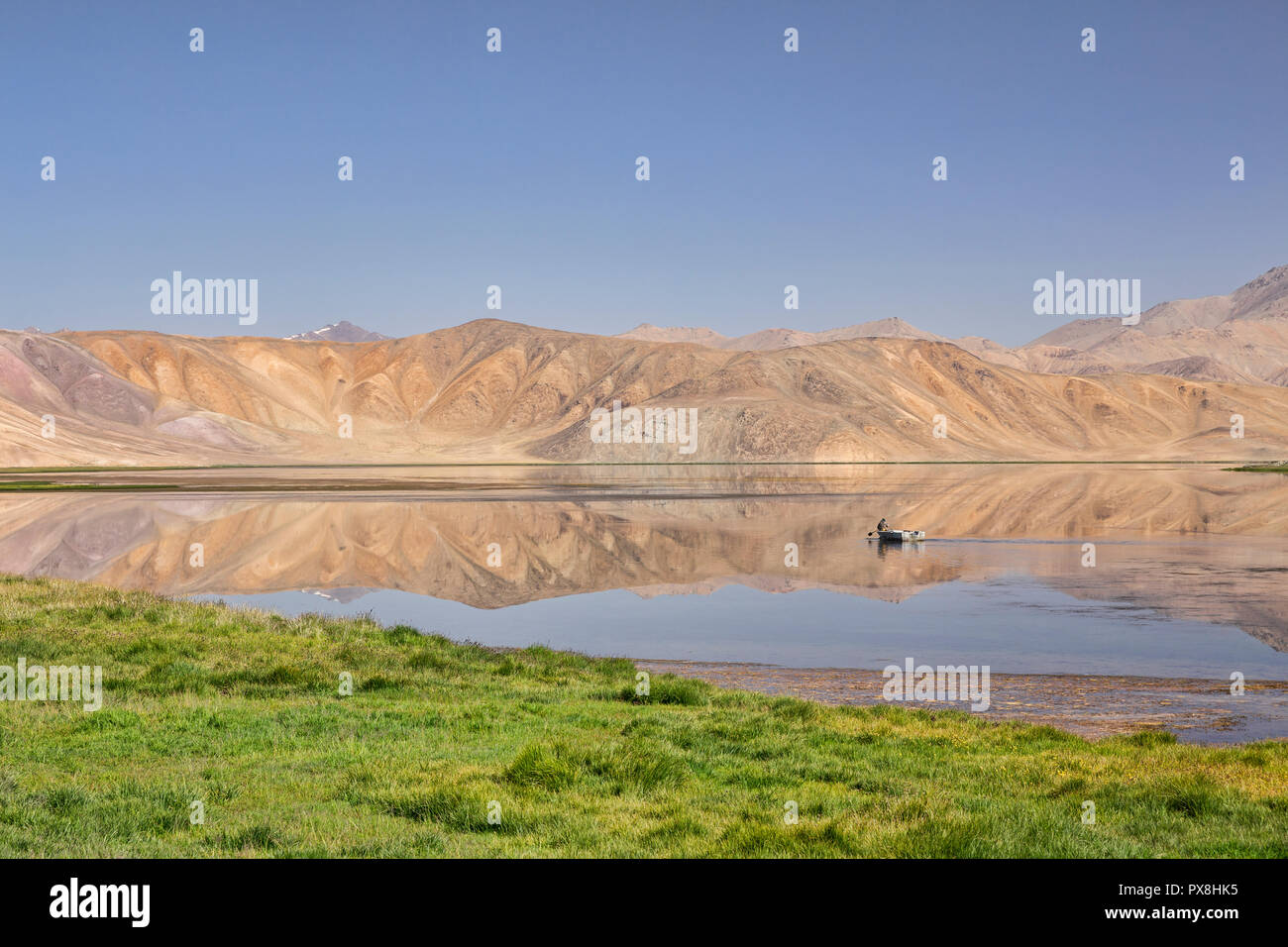 Lone fischer Zeilen Boot durch Reflexionen über Bulunkul See im oberen Gunt Tal, Bulunkul, Pamir, Pamir Highway, Tadschikistan Stockfoto