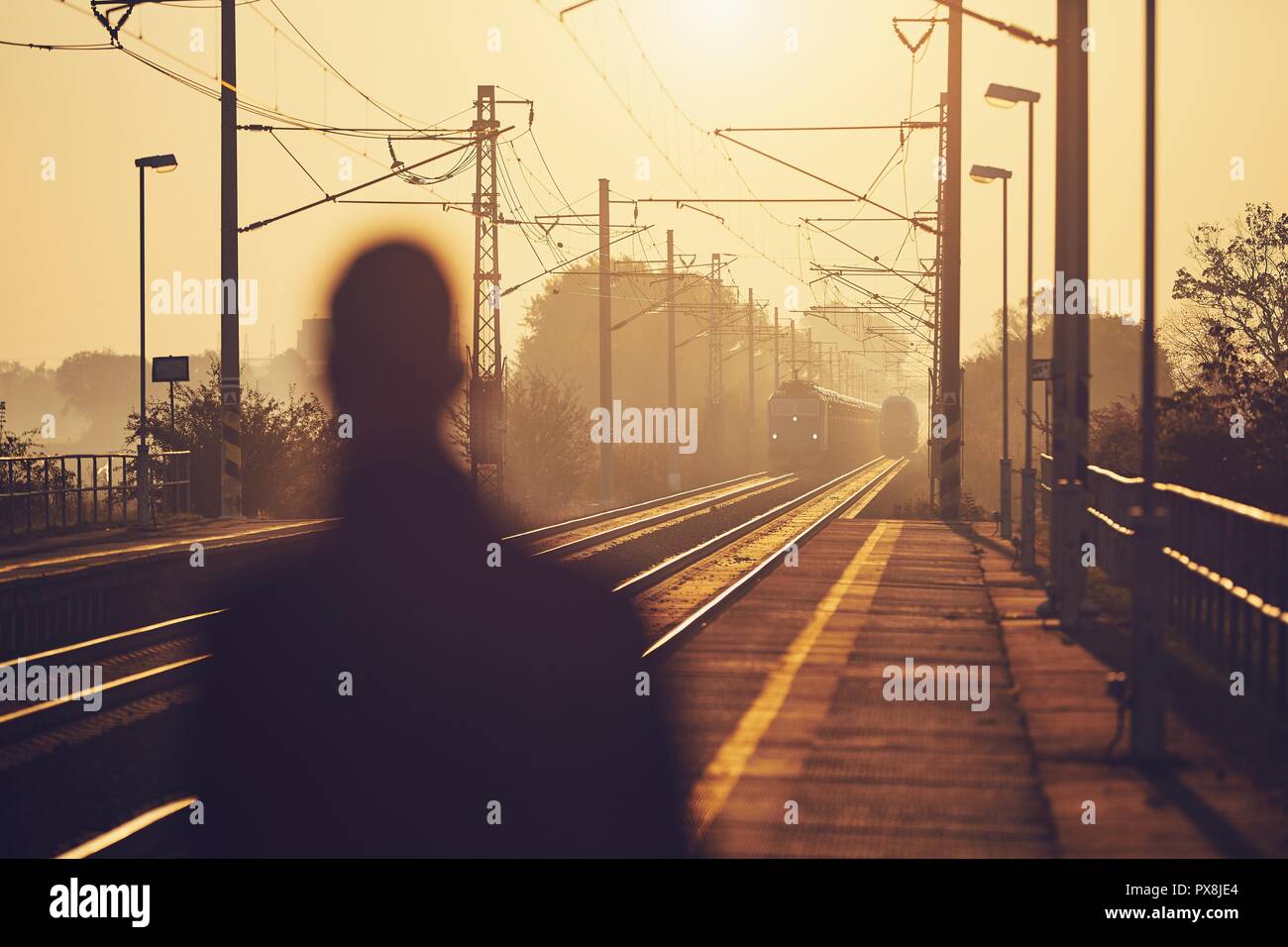 Silhouette der Mann am Bahnhof Plattform bei Sonnenaufgang warten. Stockfoto