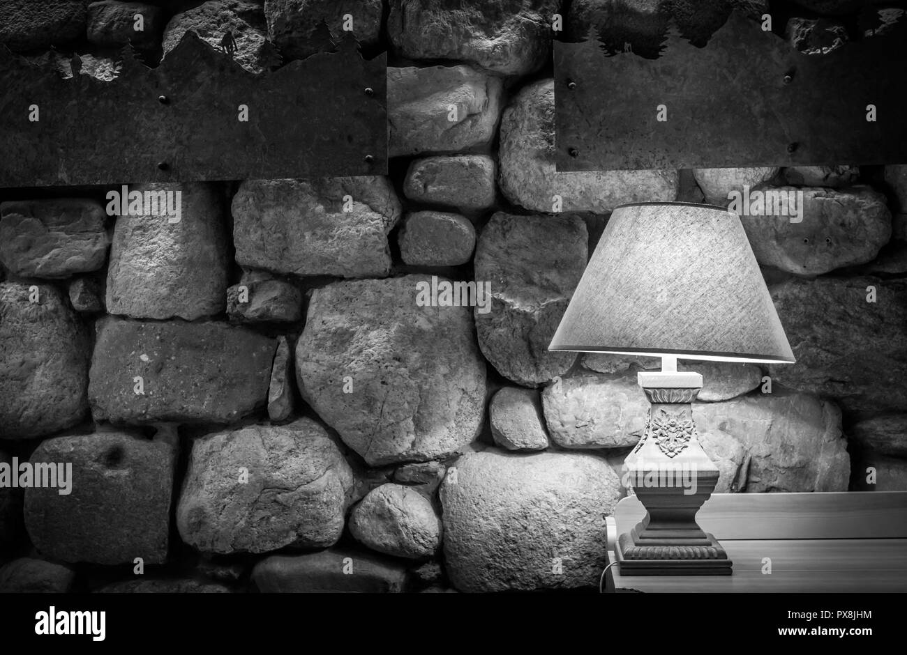 Steinmauer von stilvolle Lampe auf Holztisch, beleuchtet Stockfoto