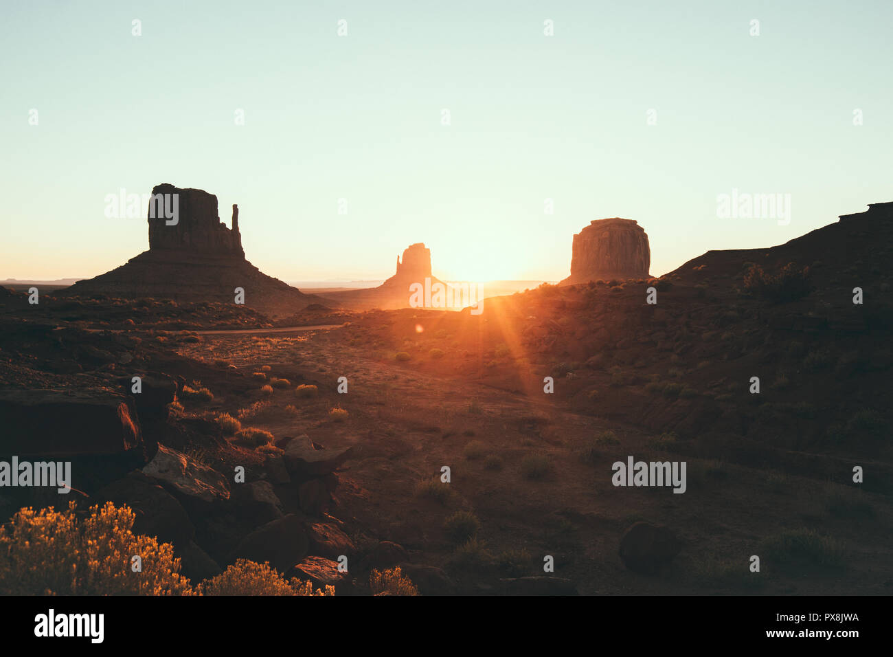 Klassische Ansicht des malerischen Monument Valley mit dem berühmten Fäustlinge und Merrick Butte im schönen goldenen Morgenlicht bei Sonnenaufgang im Sommer mit retro vin Stockfoto