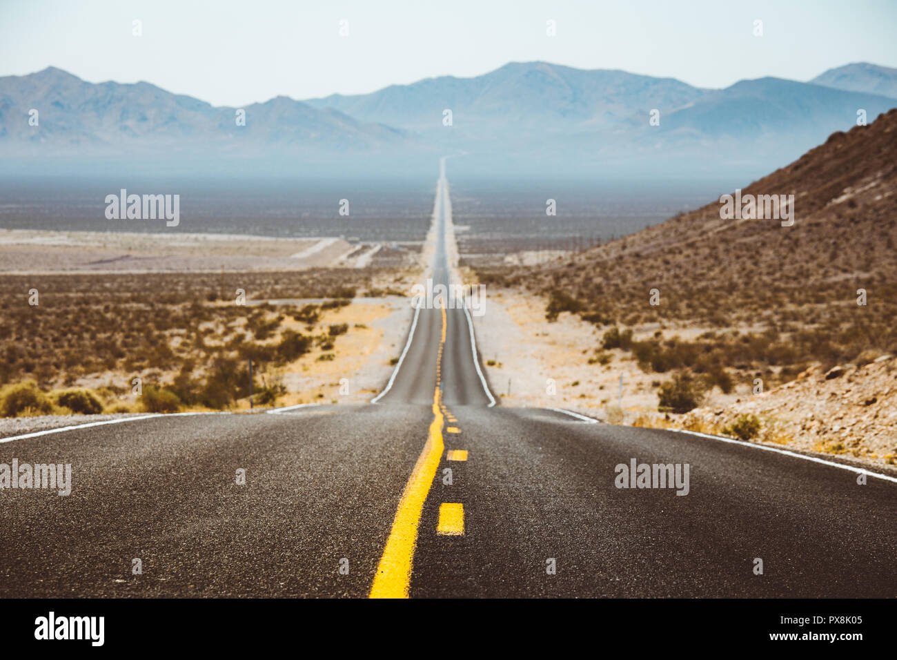Classic panorama Blick auf eine endlose gerade Straße durch die karge Landschaft des amerikanischen Südwestens mit extremer Hitze Dunst im Sommer Stockfoto Classic panorama Blick auf eine endlose gerade Straße durch die karge Landschaft des amerikanischen Südwestens mit extremer Hitze Dunst im Sommer Stockfoto
