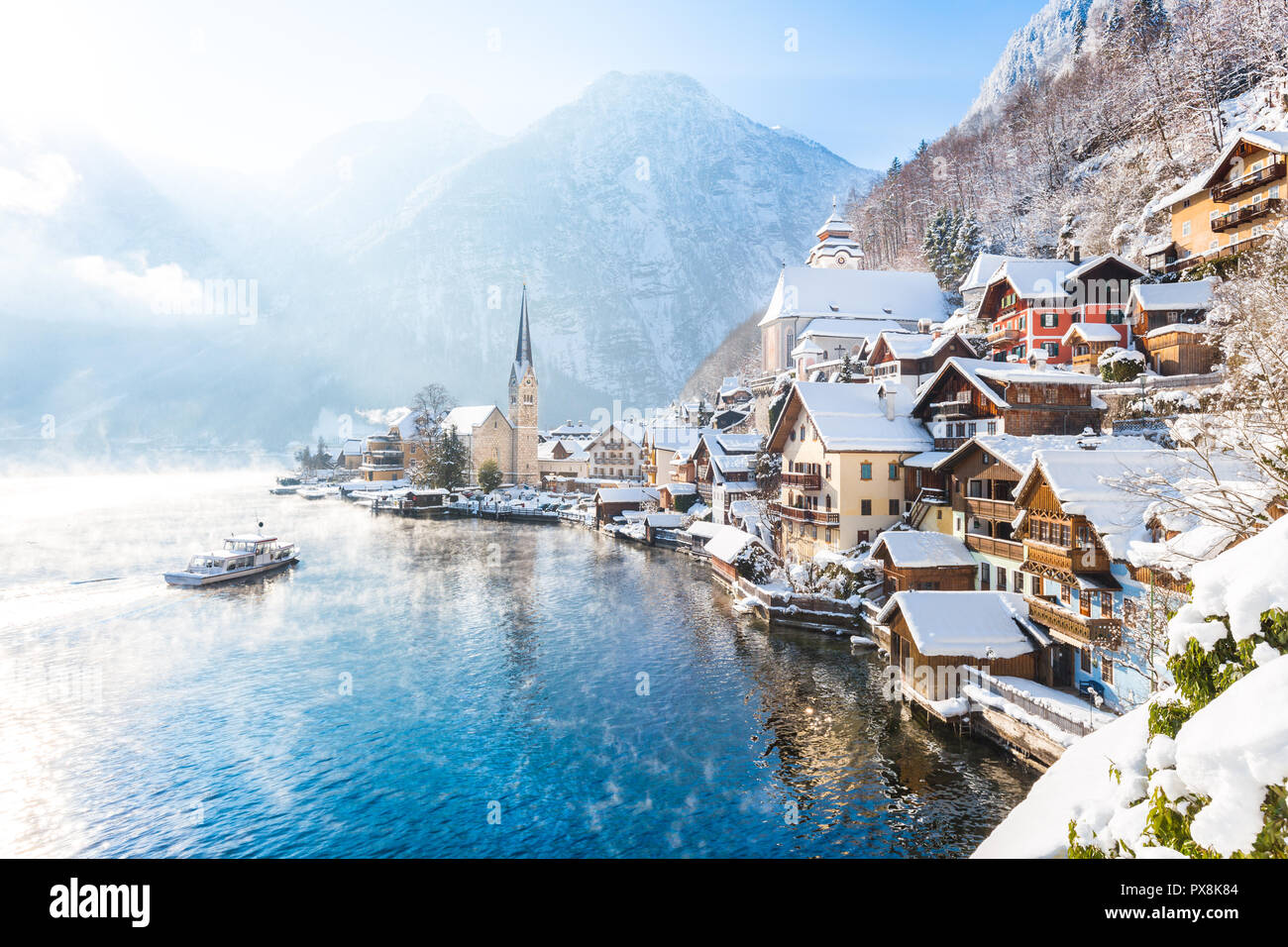Klassische Postkartenblick auf berühmte Hallstätter See Stadt in den Alpen mit Passagier Schiff auf einem schönen kalten sonnigen Tag mit blauem Himmel und Wolken im wint Stockfoto