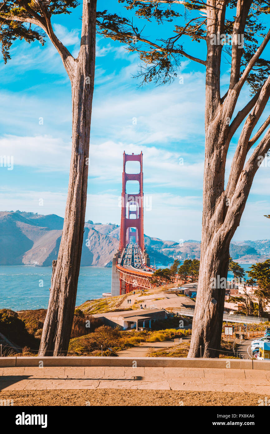 Klassische Ansicht der berühmten Golden Gate Bridge von alten Zypressen bei Scenic Presidio Park gerahmt an einem schönen sonnigen Tag mit blauen Himmel und Wolken, San F Stockfoto