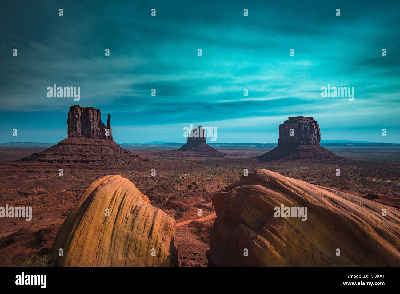 Klassische Panoramablick auf malerischen Monument Valley mit dem berühmten Fäustlinge und Merrick Butte in einer sternenklaren Nacht in schönem mystische Mondschein beleuchtet Stockfoto