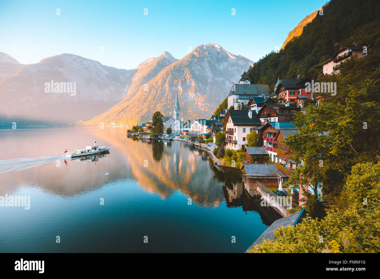 Klassische Postkarte Blick auf berühmte Hallstatt Stadt am See in den Alpen mit traditionellen Fahrgastschiff in den frühen Morgen bei Sonnenaufgang auf einem schönen d Stockfoto
