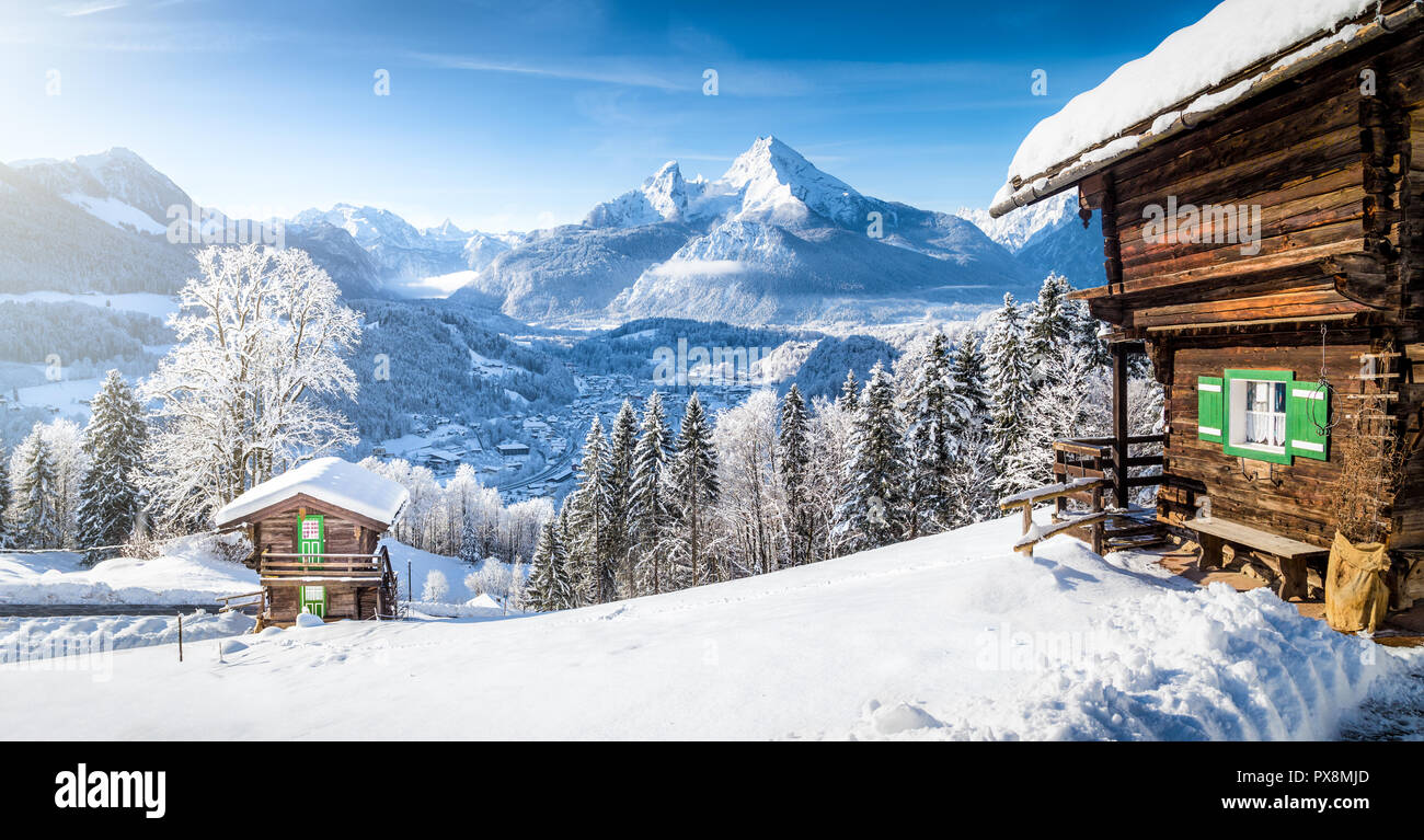 Panoramablick auf die wunderschöne Winterlandschaft Berglandschaft der Alpen mit traditionellen Mountain Chalets an einem kalten sonnigen Tag mit blauem Himmel und Clo Stockfoto