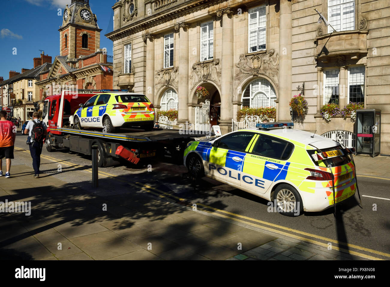 Zwei Polizeiautos, die auf eine Wiederherstellung des Fahrzeugs durch das Stadtzentrum von Crewe Großbritannien transportiert Stockfoto