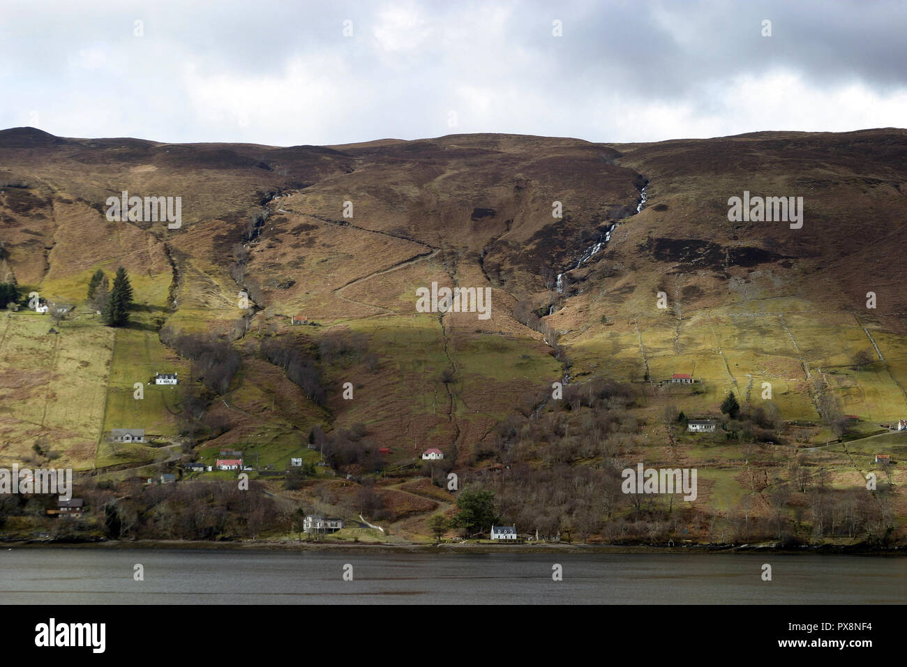 Ein Blick auf die robuste, Narben, Scottish, Hanglage mit ein paar kleinen Häusern im IT-Bereich, was bis zur Kante der ein Loch als die Sonne spielt über die Konturen des Landes. In anderen Worten; große, beeindruckende schottische Landschaft von seiner besten Seite, wie üblich. Stockfoto