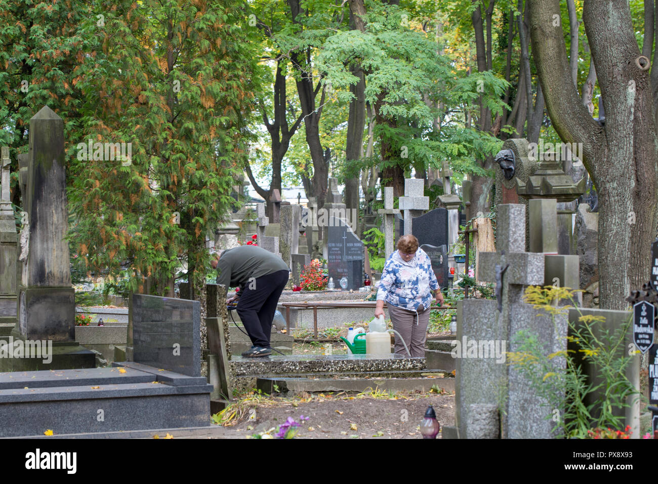 Friedhof Powazki, Warschau, Polen - Polnisch Paar reinigt eine Familie Grab in der Vorbereitung für die Allerheiligen Feier am 1. November Stockfoto