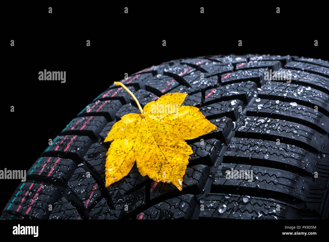 Winter Reifen rad Profil mit Herbstlaub auf schwarzem Hintergrund. Stockfoto