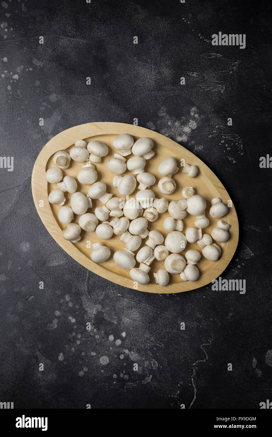 Hintergrund für das Menü. Champions Champignons auf Holz Board auf schwarzem Hintergrund Stockfoto