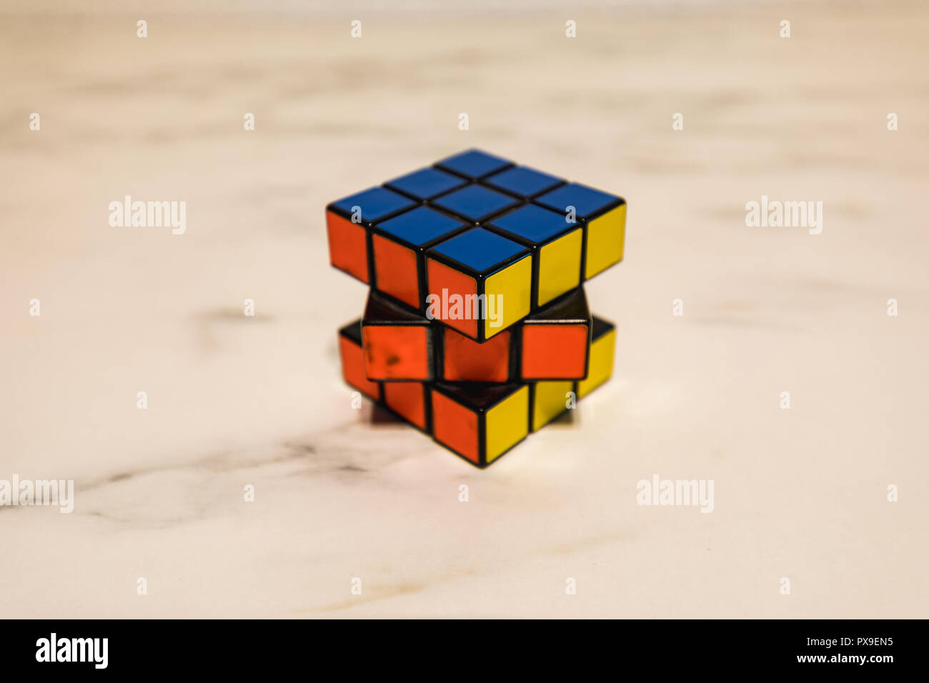 Rubik's Cube auf einer Marmorplatte, Blau, Gelb und Orange closeup Stockfoto