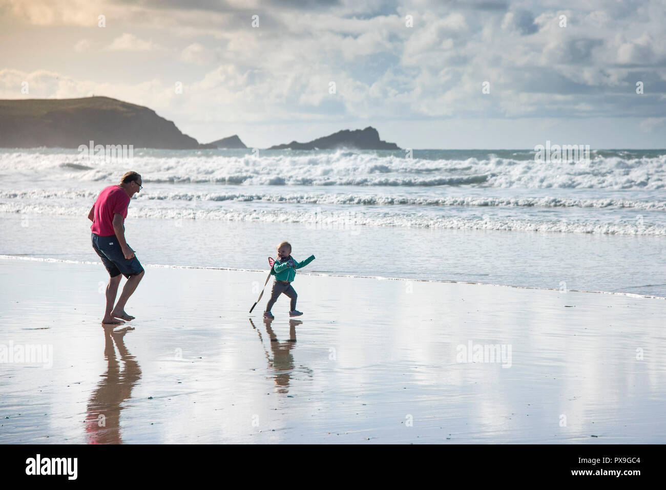Ein grossvater Spaß jagen seine Enkelin auf den Fistral Beach in Newquay in Cornwall. Stockfoto