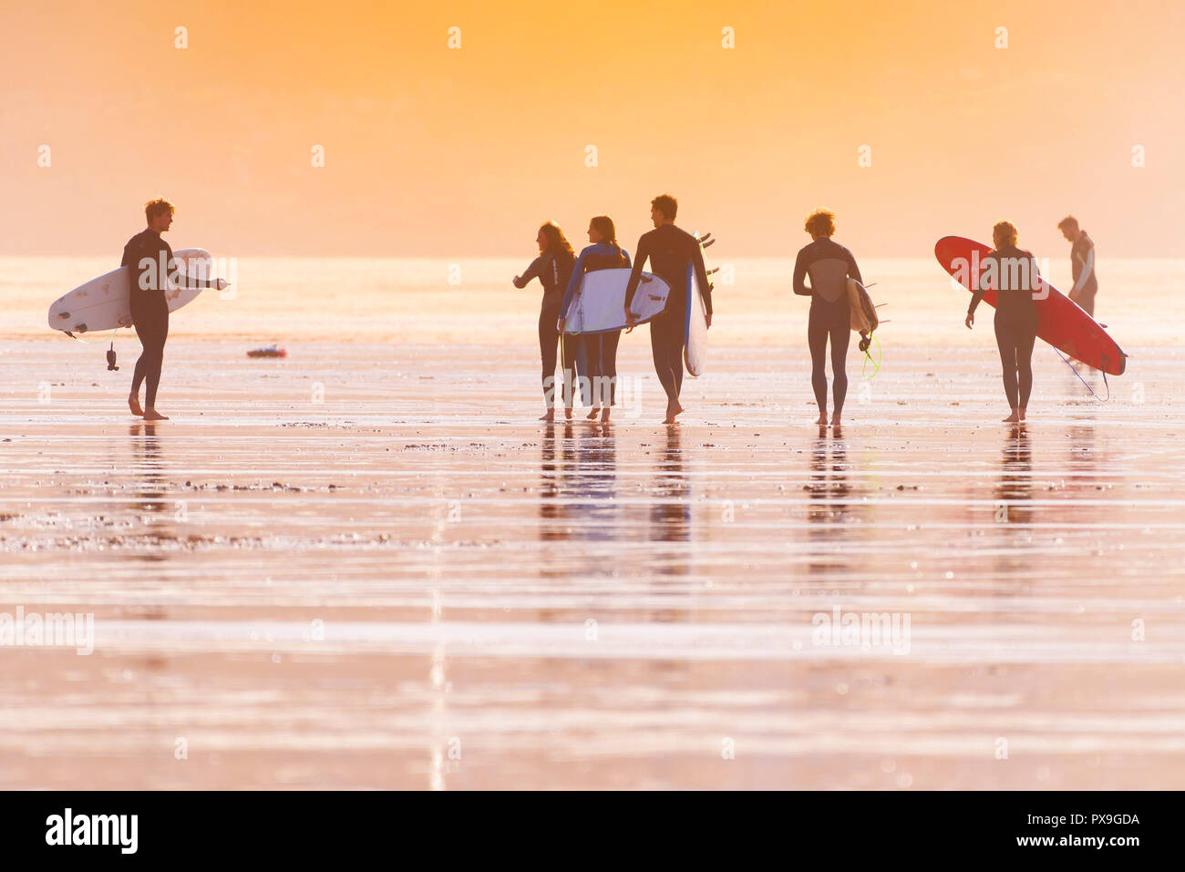 Surfen Newquay - eine Gruppe von Surfern, die ihre Surfbretter und von dort über den Fistral Beach am späten Abend die Sonne. Stockfoto