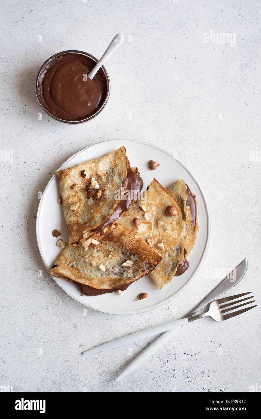 Pfannkuchen mit Schokolade und Haselnüssen. Hausgemachte dünne Crepes für Frühstück oder Dessert auf weissem, kopieren. Stockfoto