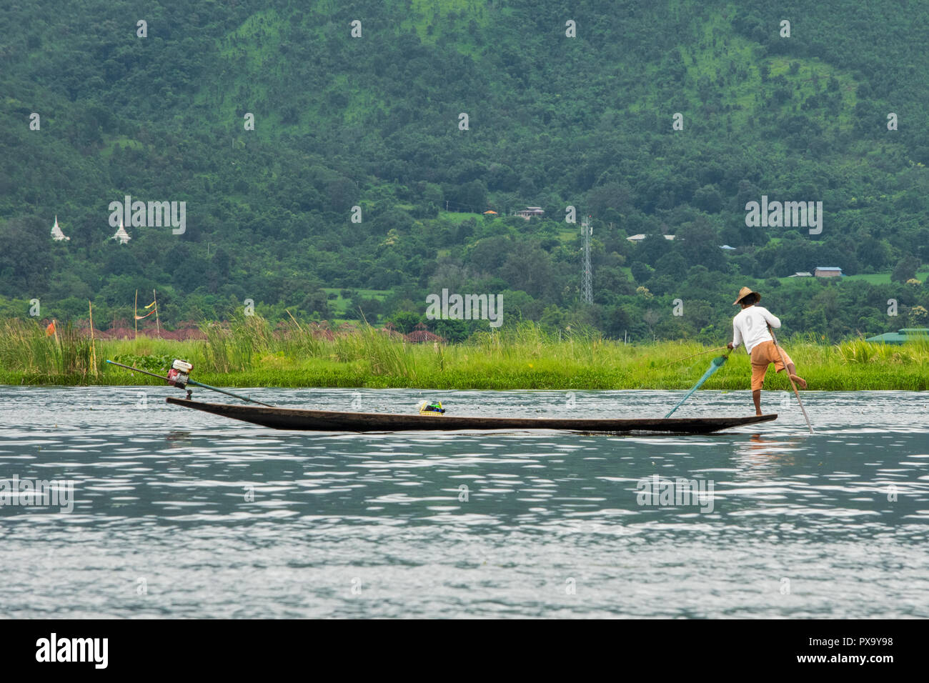 Reisen, lokale Fischer in weißem Hemd und Orange Shorts Balancieren auf einen Fuß auf die Spitze des Bootes und ziehen Netz, um Fische zu sammeln, Inle-see Burma Stockfoto