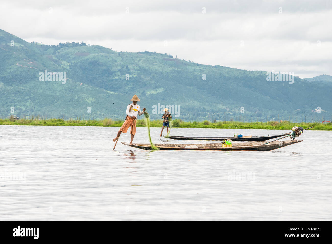 Reisen: Lokale junge Burmesische fischer Tragen von Manchester United Shirt, Lastausgleich und Lenkung Boot mit seinem Fuß in Inle See, Burma, Myanmar, Asien Stockfoto