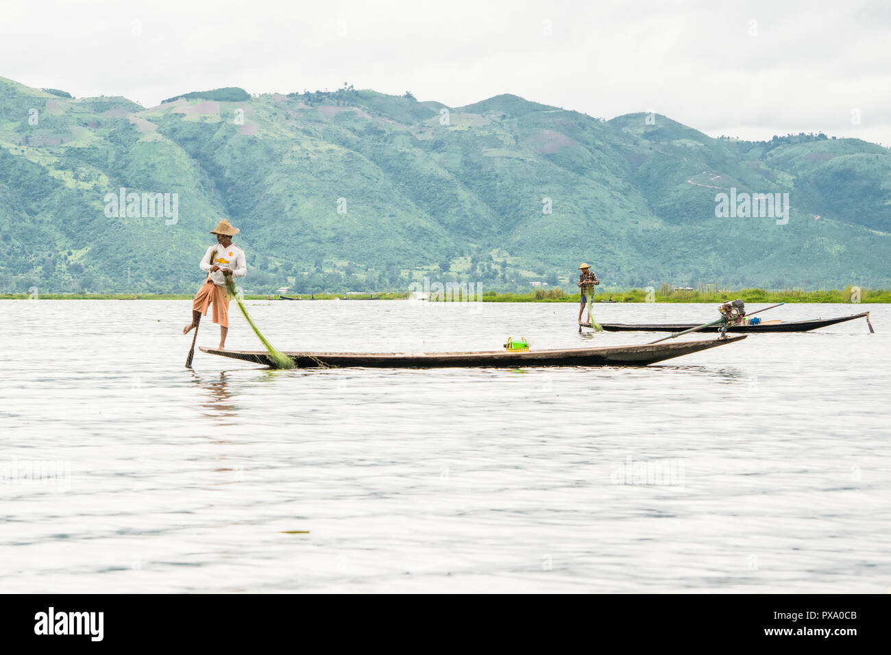 Reisen: Lokale junge Burmesische fischer Tragen von Manchester United Shirt, Lastausgleich und Lenkung Boot mit seinem Fuß in Inle See, Burma, Myanmar, Asien Stockfoto